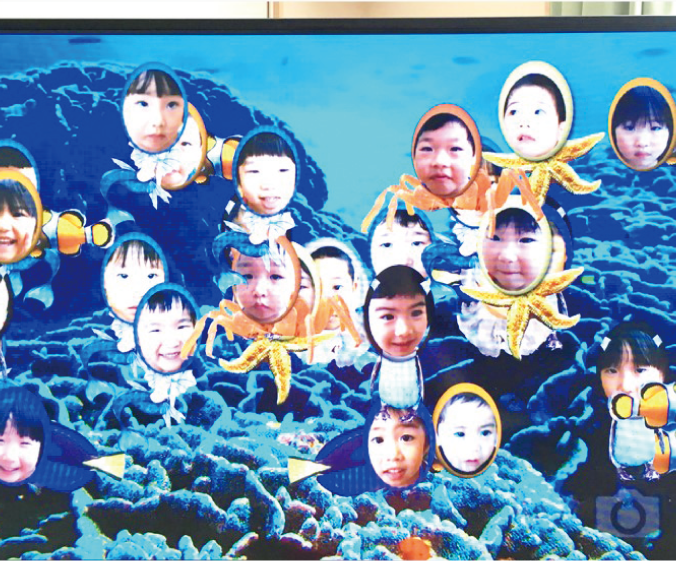 モニターの水槽で泳ぐ水族に変身した子供たちの顔写真