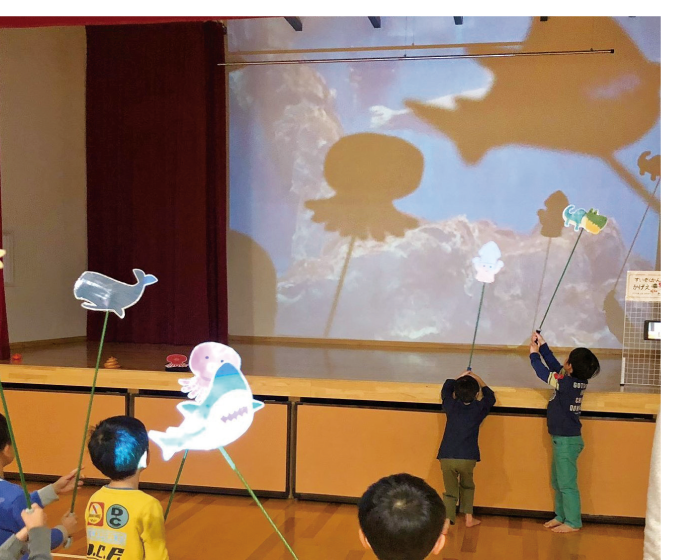 水族の紙人形で影絵をする子供たち